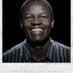 A man smiles broadly while looking at the camera. He is wearing a striped shirt. The image has a caption at the bottom that reads: "I wish to become a father one day and to be a good mentor to my children." The text at the top right corner reads: "Abdul / Age: 31 / Uganda".