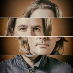 A fragmented portrait of a person with shoulder-length hair, divided into four horizontal sections. Each section of the face is slightly misaligned, creating a visually striking collage effect, against a warm brown background. The person wears a blue denim shirt.